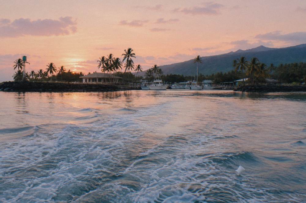 calm open ocean surface at sunrise with a boat wake trailing behind
