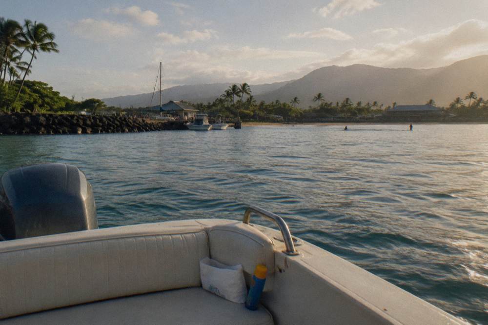 calm summer ocean surface near a shark tour boat with distant north shore coastline