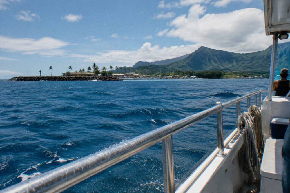 Deep open ocean water far from the Oahu coastline under scattered clouds