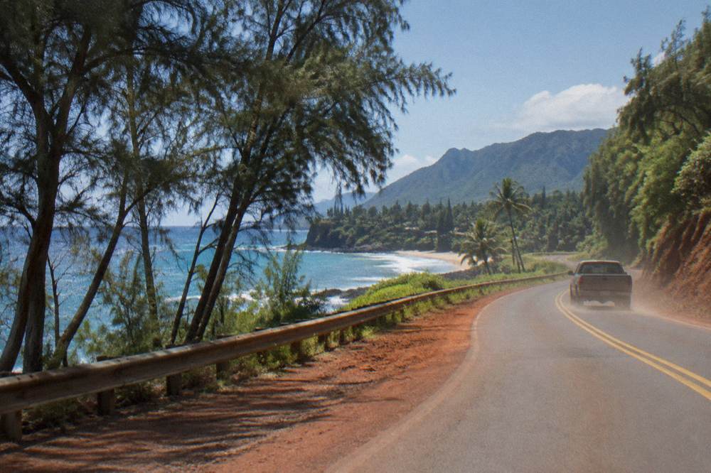 A coastal highway curving along a green shoreline with blue ocean
