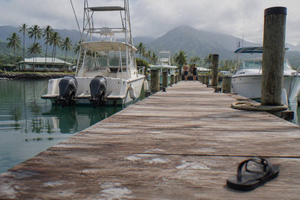 Wooden dock leading out to moored boats on calm harbor water
