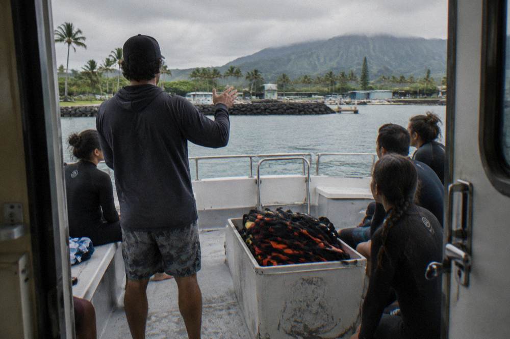 Crew members giving a safety briefing to passengers on the deck of a shark tour boat