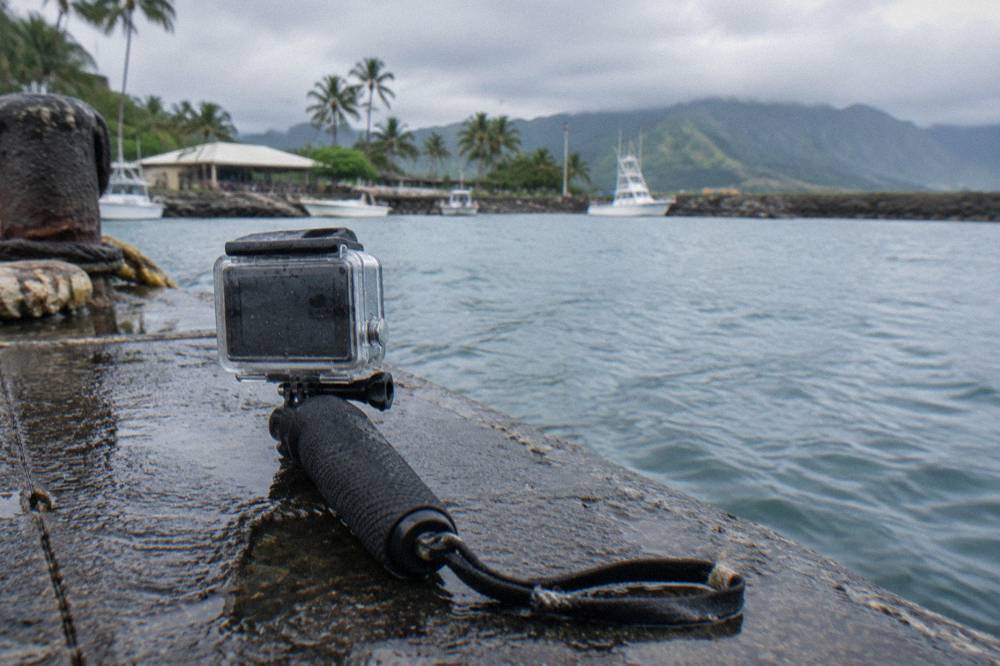 A GoPro in a clear housing mounted on a short hand grip above open ocean
