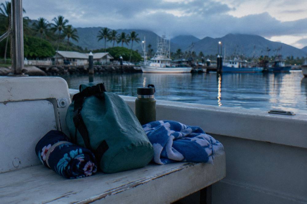 Swimsuit, towel and dry bag packed on a boat bench before departure