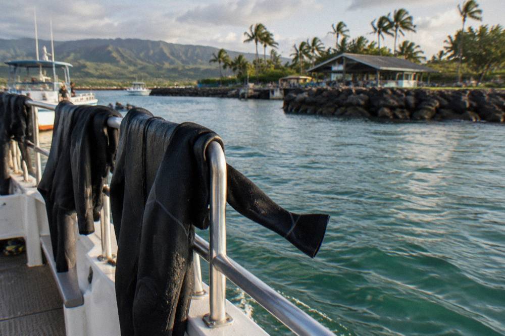 Wetsuits hanging on railings along the side of a shark tour boat